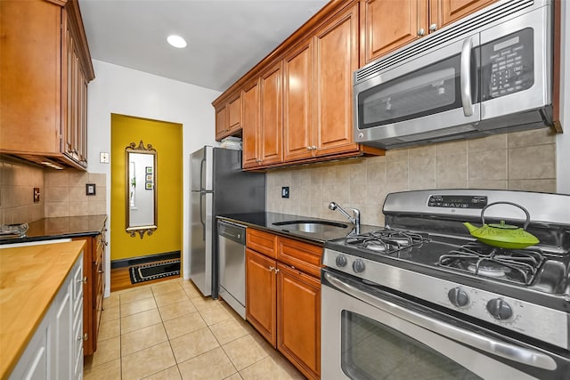 kitchen featuring tasteful backsplash, wooden counters, appliances with stainless steel finishes, light tile patterned flooring, and sink