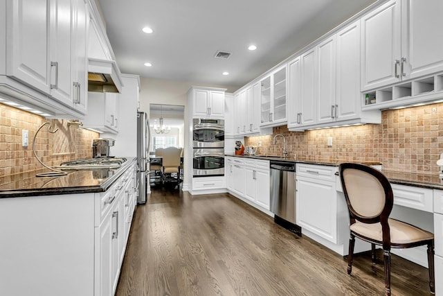 kitchen featuring white cabinetry, sink, dark hardwood / wood-style flooring, dark stone counters, and appliances with stainless steel finishes