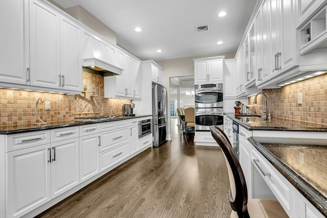 kitchen featuring white cabinets, stainless steel appliances, dark stone countertops, and sink