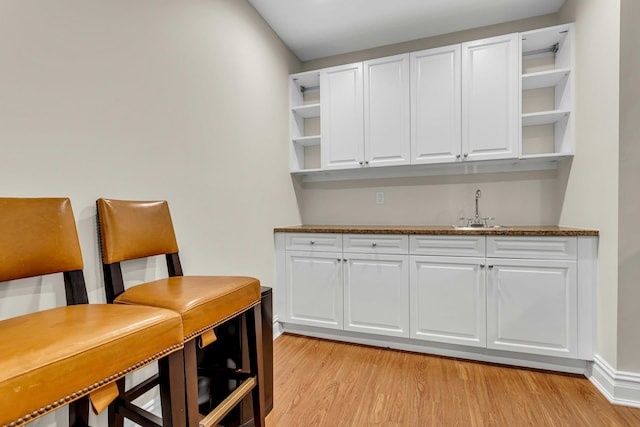 bar featuring white cabinetry, sink, and dark stone counters