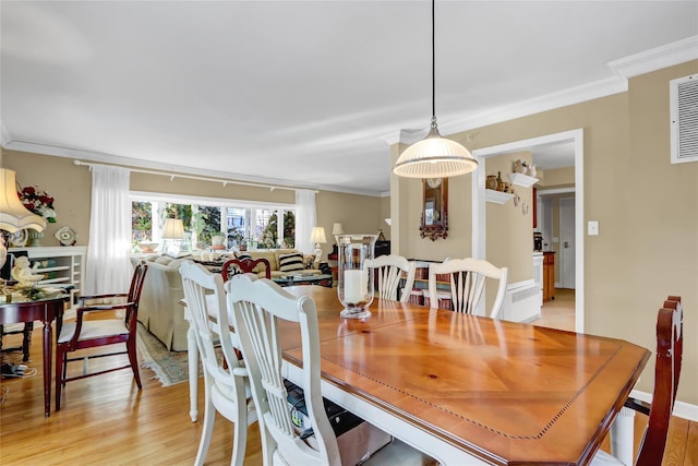 dining room with ornamental molding and light hardwood / wood-style flooring