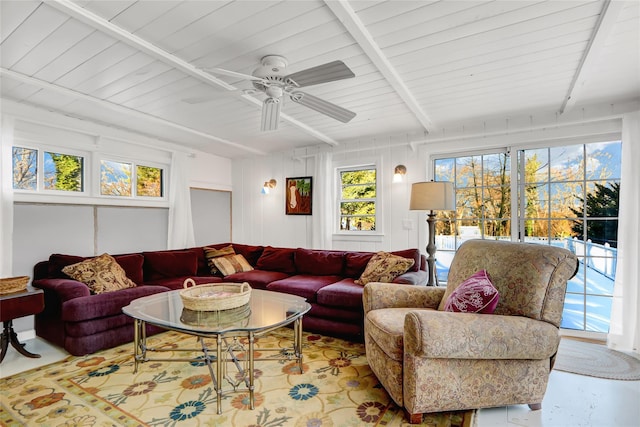 living room featuring beamed ceiling, ceiling fan, and a healthy amount of sunlight