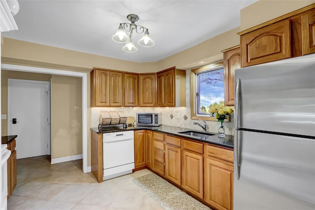 kitchen with appliances with stainless steel finishes, decorative light fixtures, sink, backsplash, and a notable chandelier