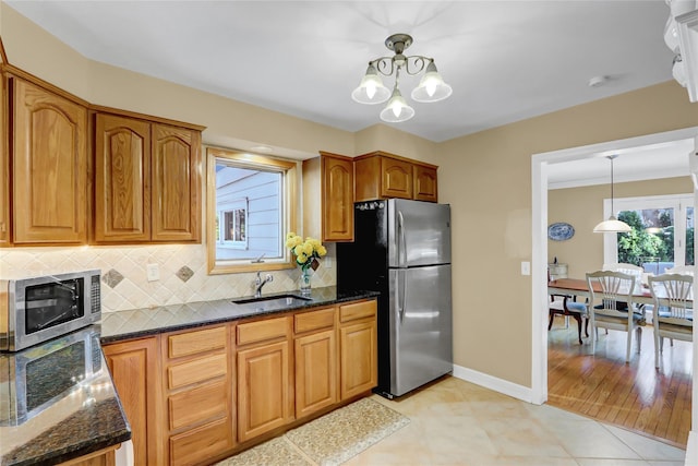 kitchen with sink, light tile patterned floors, backsplash, stainless steel appliances, and decorative light fixtures