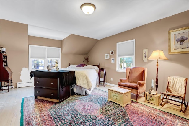 bedroom featuring light hardwood / wood-style flooring, a baseboard radiator, and vaulted ceiling