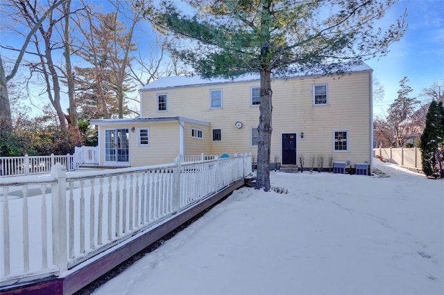 snow covered back of property featuring central AC