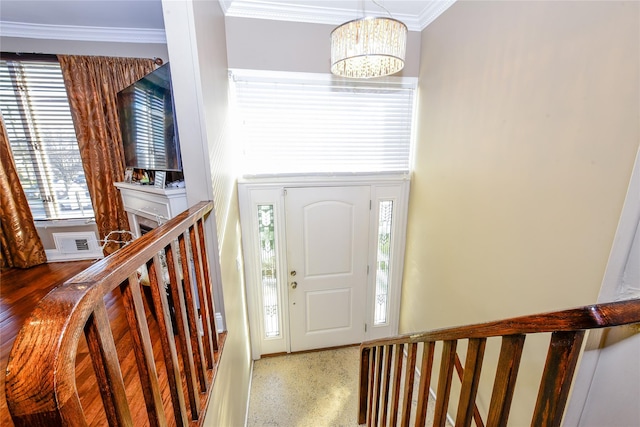 foyer entrance with a chandelier and crown molding