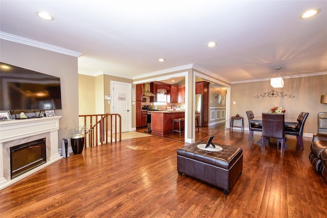 living room featuring dark wood-type flooring, crown molding, and a fireplace