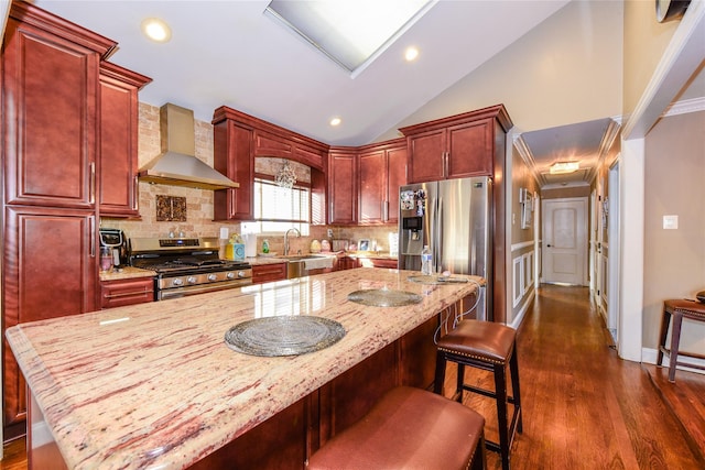 kitchen featuring appliances with stainless steel finishes, tasteful backsplash, lofted ceiling, light stone countertops, and wall chimney exhaust hood