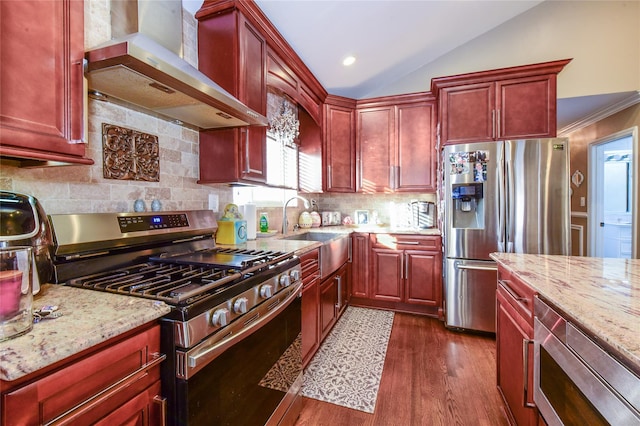 kitchen with light stone countertops, wall chimney exhaust hood, stainless steel appliances, sink, and vaulted ceiling