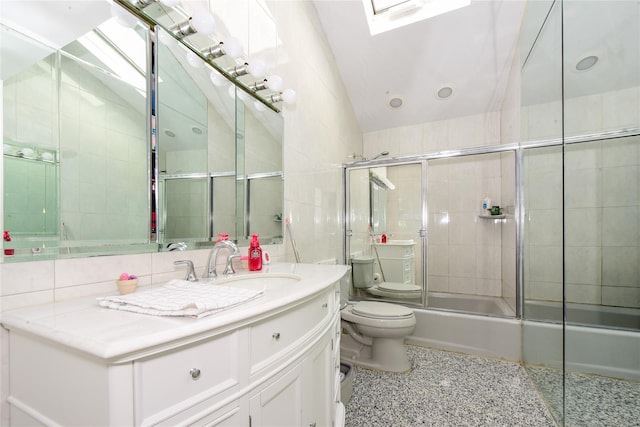 full bathroom featuring vaulted ceiling with skylight, bath / shower combo with glass door, toilet, and tile walls