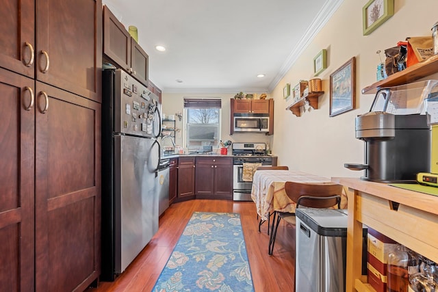 kitchen with ornamental molding, light wood-type flooring, and appliances with stainless steel finishes