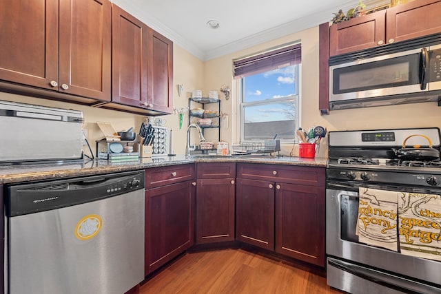 kitchen featuring stainless steel appliances, crown molding, sink, stone counters, and light hardwood / wood-style floors