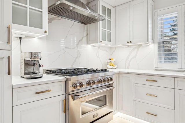 kitchen with white cabinetry, wall chimney range hood, high end stainless steel range oven, and tasteful backsplash