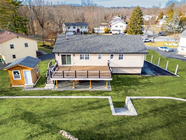 rear view of house with a lawn, a shed, and a deck