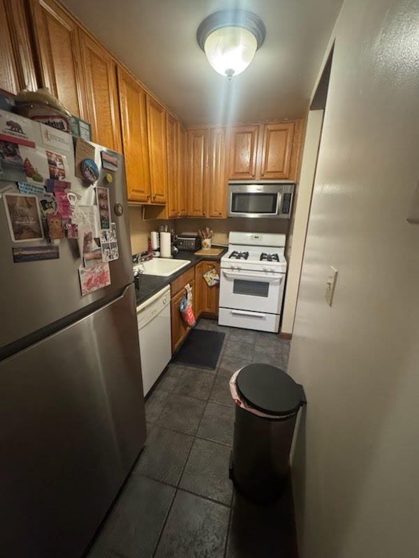 kitchen with sink, dark tile patterned floors, and appliances with stainless steel finishes