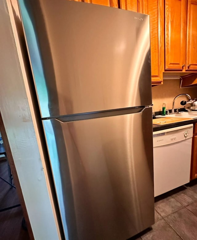 kitchen featuring dishwasher, light tile patterned floors, sink, and stainless steel refrigerator