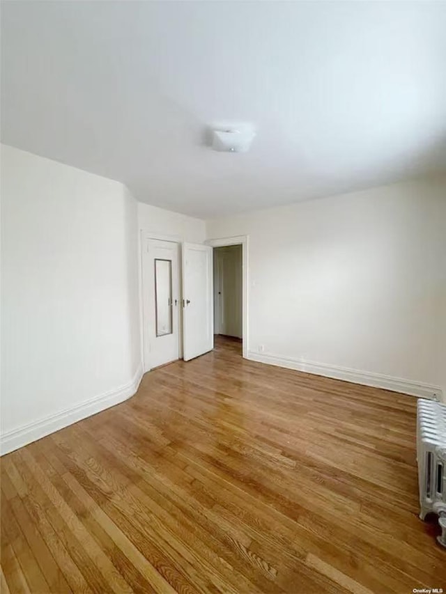 spare room with hardwood / wood-style floors and radiator heating unit