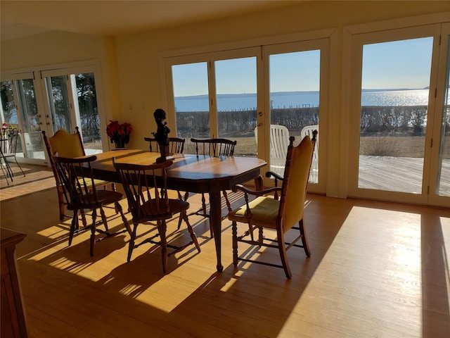 dining room featuring hardwood / wood-style flooring, french doors, and a water view