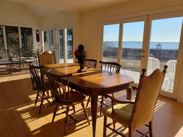 dining area featuring light wood-type flooring, french doors, and vaulted ceiling