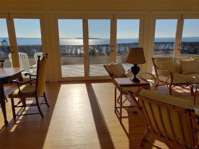 sunroom featuring a water view and french doors