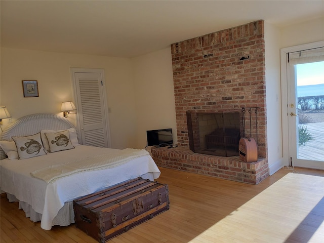 bedroom featuring a fireplace, hardwood / wood-style flooring, access to outside, and a closet