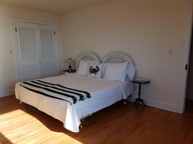 bedroom featuring wood finished floors, a closet, and baseboards