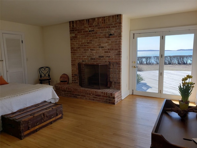 bedroom featuring light wood-style flooring, a fireplace, and access to outside