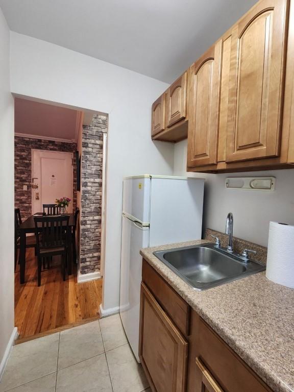 kitchen with light tile patterned floors, white fridge, and sink