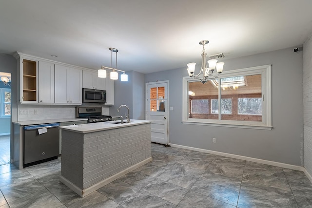 kitchen featuring an island with sink, sink, white cabinets, hanging light fixtures, and stainless steel appliances