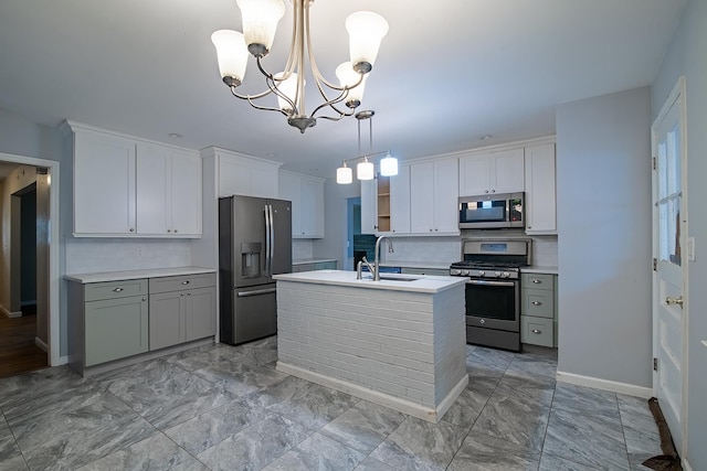 kitchen featuring sink, white cabinetry, stainless steel appliances, a center island with sink, and decorative light fixtures