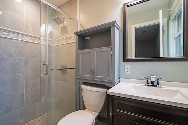 bathroom featuring toilet, vanity, and a shower with shower door