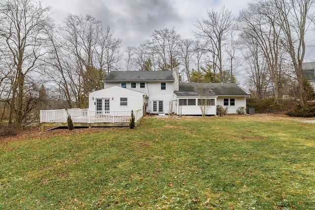 back of property featuring a lawn, a sunroom, and a deck