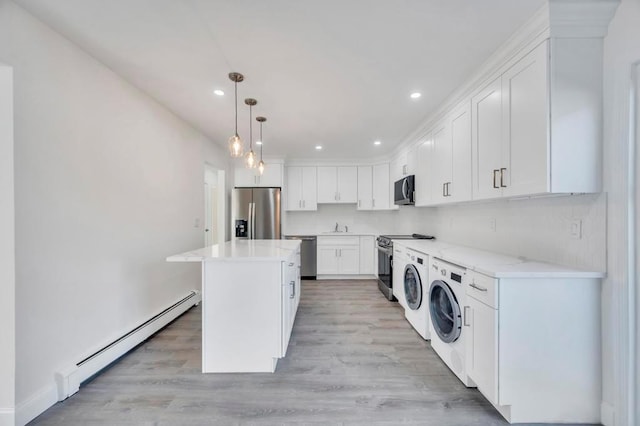 clothes washing area featuring washing machine and dryer, sink, a baseboard radiator, and light hardwood / wood-style floors