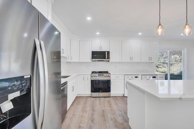 kitchen with light stone counters, appliances with stainless steel finishes, pendant lighting, white cabinets, and light wood-type flooring