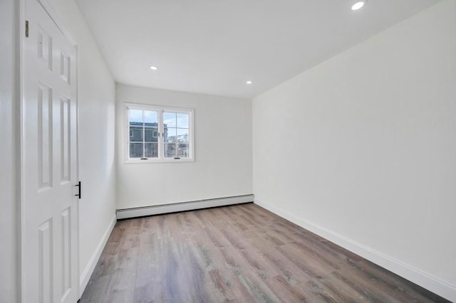 empty room with light wood-type flooring and a baseboard heating unit