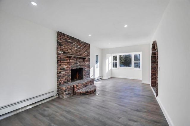 unfurnished living room featuring a fireplace, dark wood-type flooring, and a baseboard heating unit