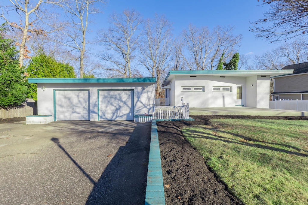 ranch-style house featuring a front lawn, a garage, and an outdoor structure