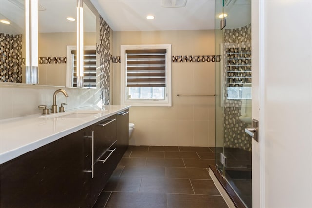 bathroom featuring tile patterned flooring, vanity, toilet, and walk in shower