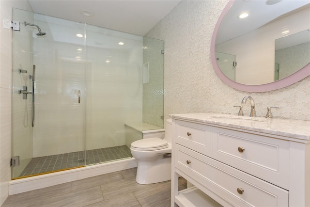 bathroom with vanity, toilet, and a shower with door