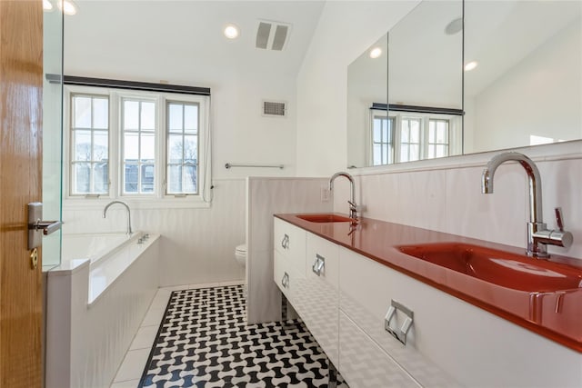 bathroom with tile patterned floors, toilet, a tub to relax in, and vaulted ceiling