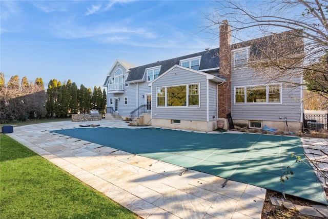 rear view of house with a patio area and a covered pool