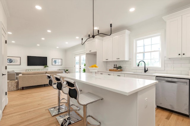 kitchen featuring dishwasher, a center island, sink, decorative light fixtures, and white cabinetry