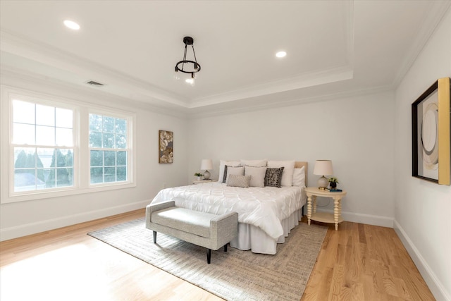 bedroom featuring a raised ceiling, crown molding, and light wood-type flooring