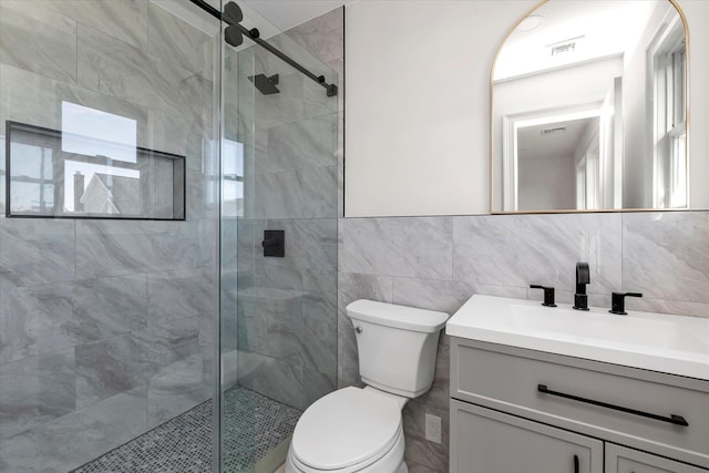 bathroom featuring walk in shower, vanity, tile walls, and toilet