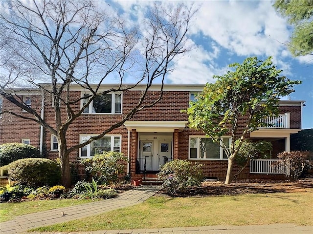 view of front of property featuring a balcony and a front lawn