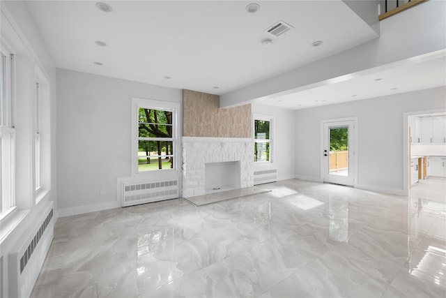 unfurnished living room featuring a fireplace and radiator