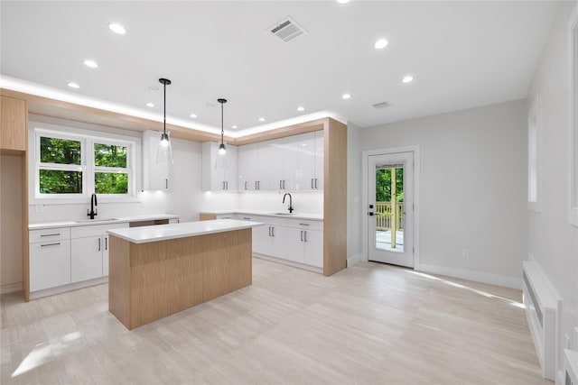 kitchen with pendant lighting, a center island, white cabinetry, and sink