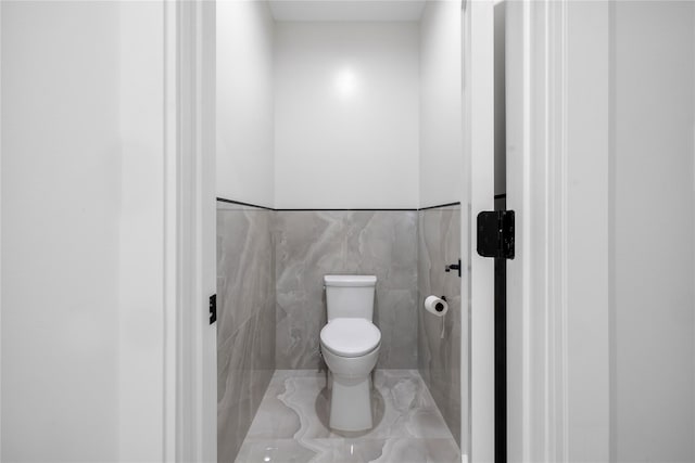 bathroom featuring toilet and tile walls