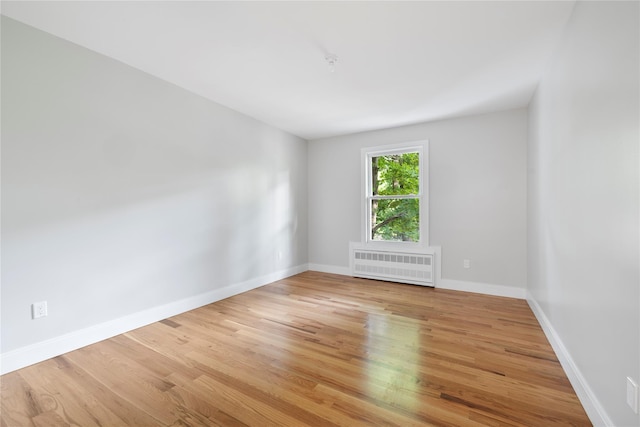 spare room featuring radiator and light hardwood / wood-style flooring